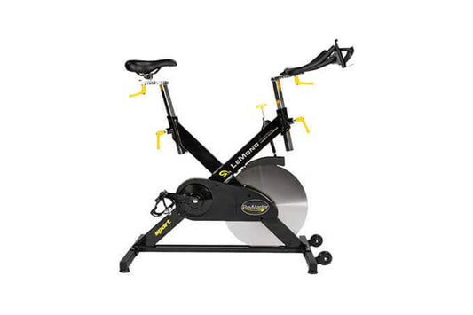 Black and yellow indoor exercise bike with drop handlebars, adjustable seat, and large flywheel, front view on white backgrou