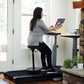 Woman in gray sweater and black pants using LifeSpan TR1000-DT7 treadmill desk with laptop in bright office space