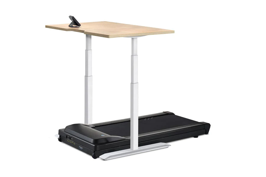 Adjustable height standing desk with light wood top and silver metal frame mounted above black treadmill base