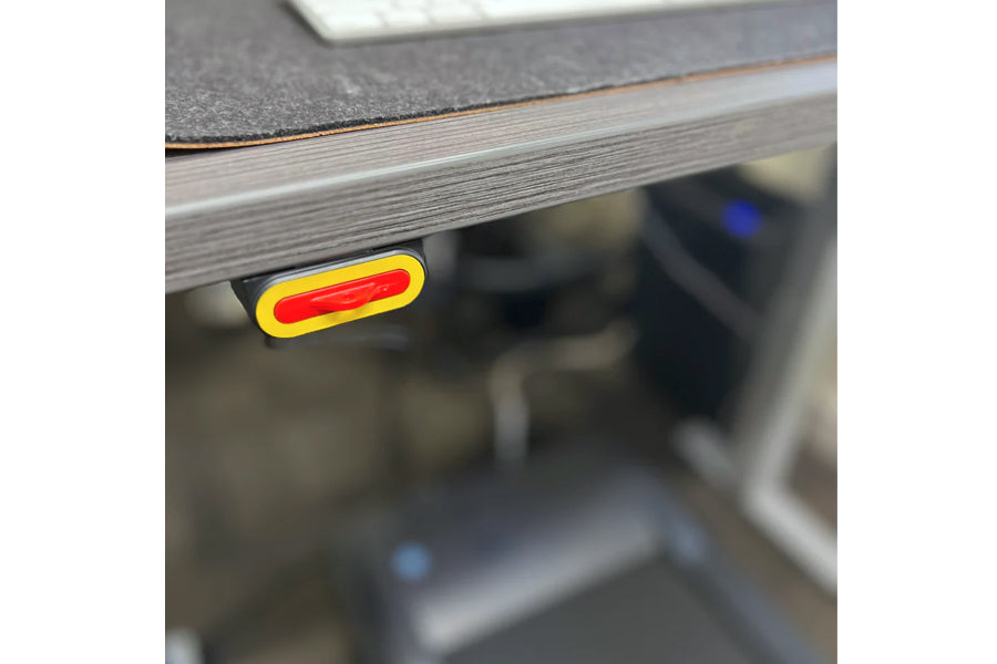 Yellow and red rounded rectangular power button on black desk treadmill base