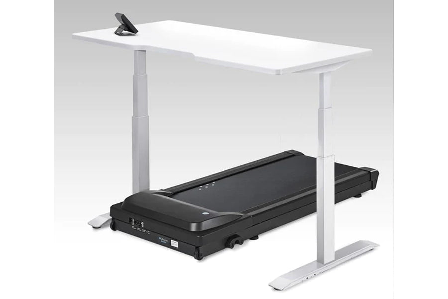 White desktop treadmill desk with black treadmill base and silver metal frame, featuring phone holder on surface, shown on gr