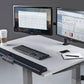 White desktop treadmill with black motorized base, dual monitors displaying spreadsheets, wireless keyboard, coffee cup, and 