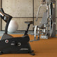 Black Life Fitness upright exercise bike with digital display in modern gym setting with concrete walls