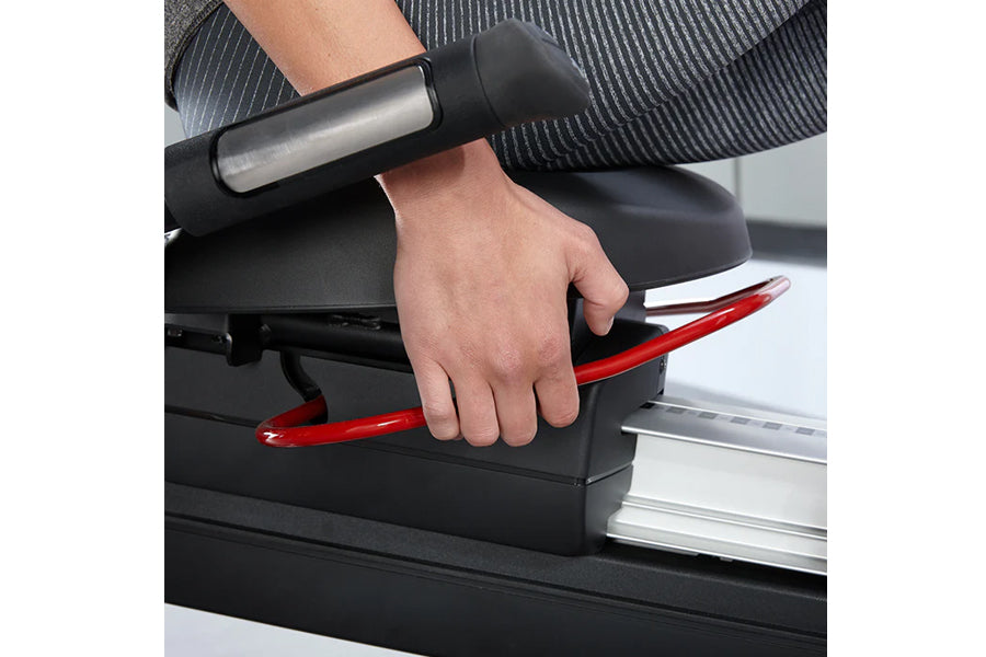 Person's hand gripping red and black handle of stationary recumbent exercise bike, worn by model during workout