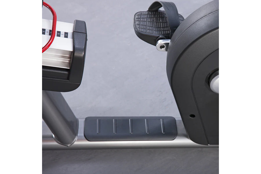 Life Fitness recumbent exercise bike with gray padded seat, footrest pedals, and control console with red cable on white back