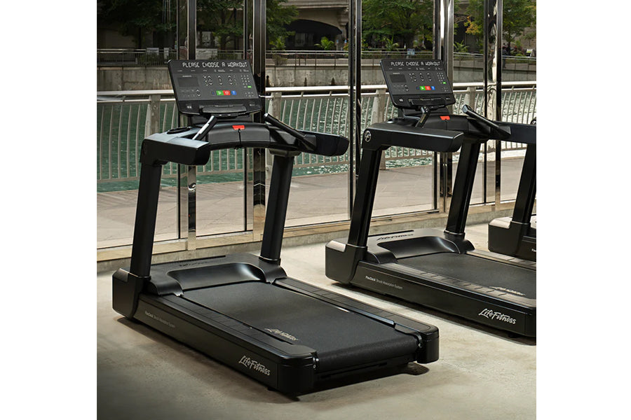 Black Life Fitness club treadmill with digital display console, shown in gym setting with mirrors and windows
