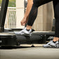 Person wearing black textured leggings and white sneakers using Life Fitness treadmill in gym studio setting