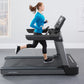 Woman running on black Life Fitness Club Series treadmill, wearing bright blue long-sleeve top and black capri leggings