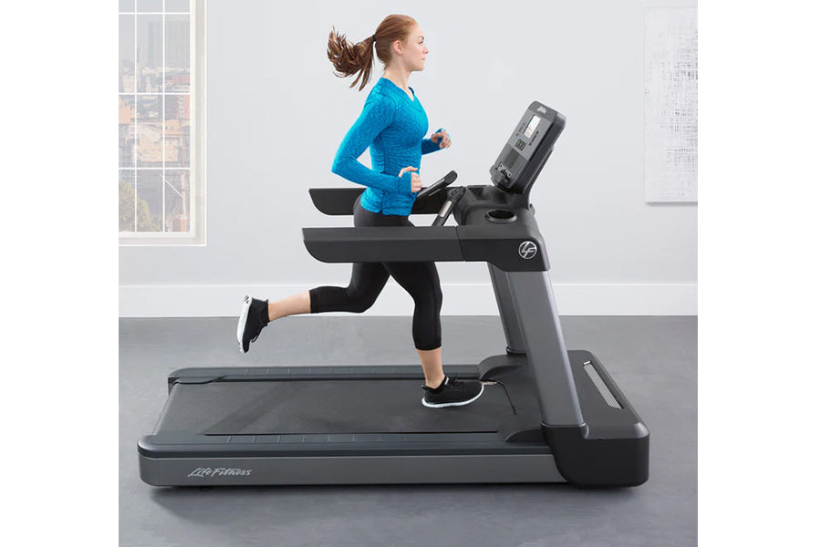 Woman running on black Life Fitness Club Series treadmill, wearing bright blue long-sleeve top and black capri leggings