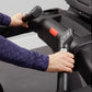 Person wearing navy sleeve holding black treadmill handlebar with digital display and red emergency stop button