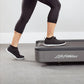 Woman wearing black capri leggings and black sneakers with white sole, exercising on Life Fitness treadmill