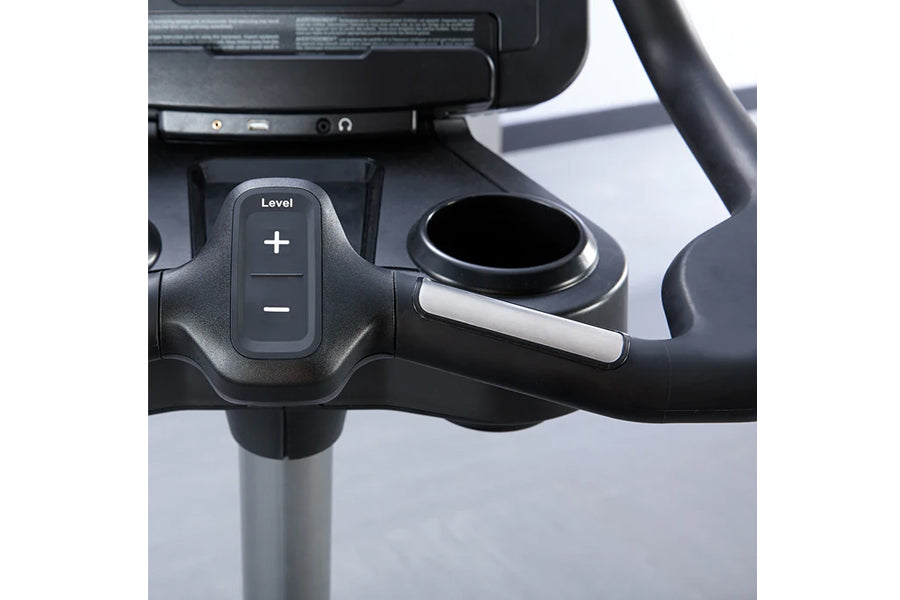 Black upright exercise bike handlebar with level adjustment controls and digital display console mounted on silver pole