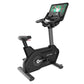 Black upright exercise bike with gray base, adjustable seat, and digital touchscreen display mounted on vertical console show