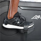 Black and white lace-up running shoe with white sole, worn on foot on exercise bike pedal