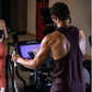 Man in burgundy sleeveless tank top using Life Fitness elliptical machine with digital display in gym setting