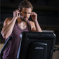 Man wearing burgundy sleeveless tank top using black Life Fitness elliptical machine, indoors