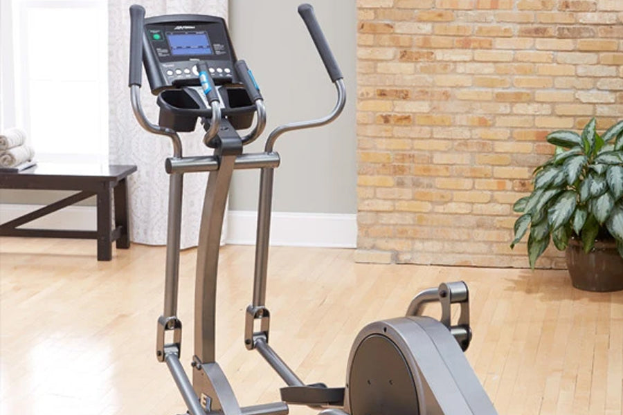 Life Fitness E1 elliptical cross-trainer with black console, gray frame and handlebars, displayed in home gym setting with br