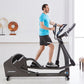 Man in blue t-shirt using black and white Life Fitness E5 elliptical machine in bright fitness studio setting