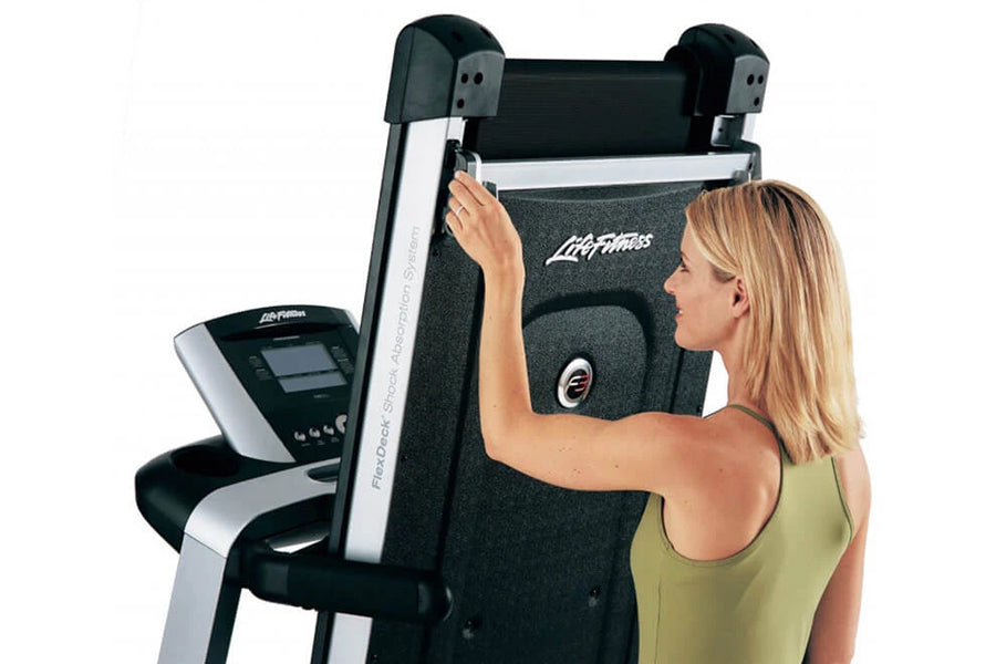 Woman in yellow tank top using Life Fitness folding treadmill with black and silver frame and digital console