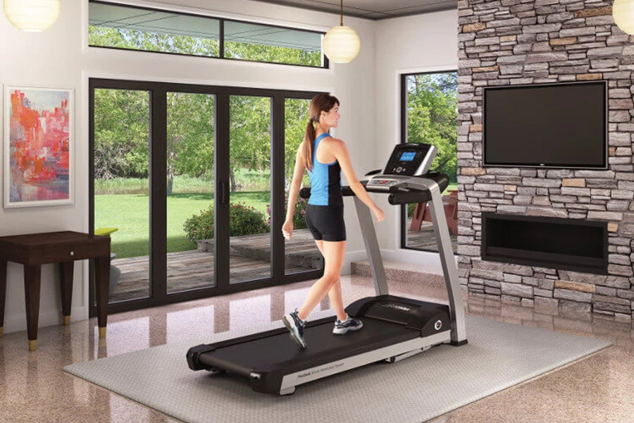 Woman running on Life Fitness F3 folding treadmill with black belt and silver frame in modern home gym