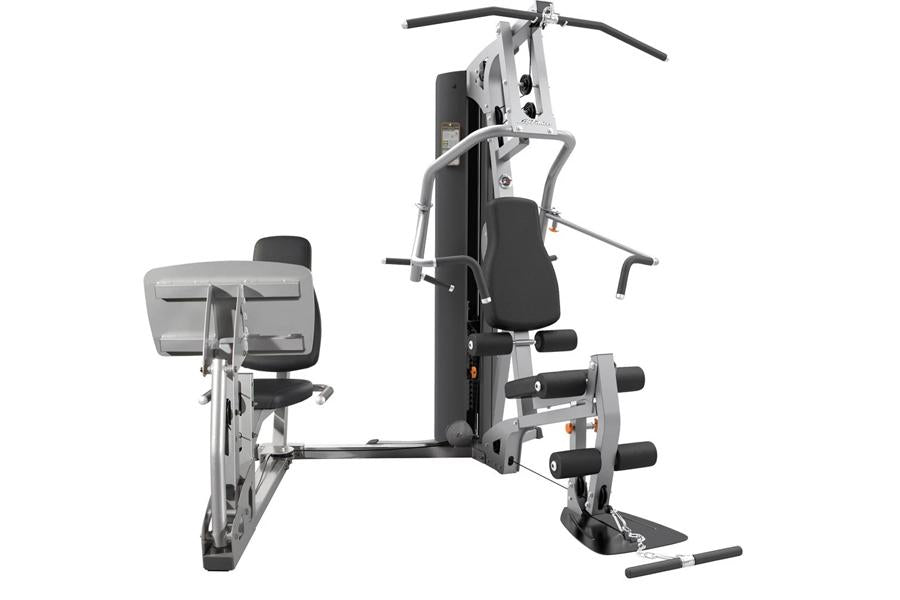 Multi-station home gym with white and black frame, padded seat, chest press, leg extension, and pull-down bar on white backgr