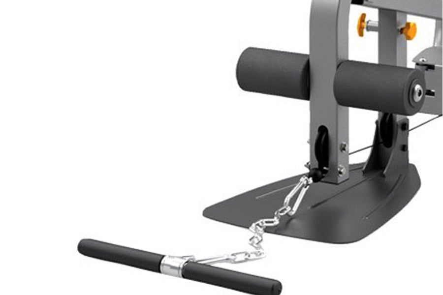 Gray and black home gym machine with padded handles, footplate, and gold pulleys, shown with detached cable attachment on whi