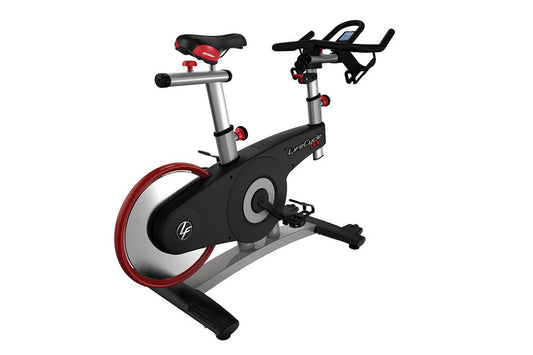 Life Fitness LifeCycle GX stationary bike with black frame, red wheel trim, silver handlebars, and red padded seat on white b