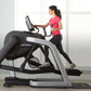 Woman in pink top and black leggings using Life Fitness elliptical trainer with digital display in bright studio setting