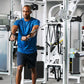 Man in blue t-shirt using Cybex Prestige dual adjustable pulley machine in gym setting surrounded by fitness equipment