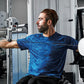 Man wearing blue patterned athletic shirt using dual adjustable pulley machine in gym setting