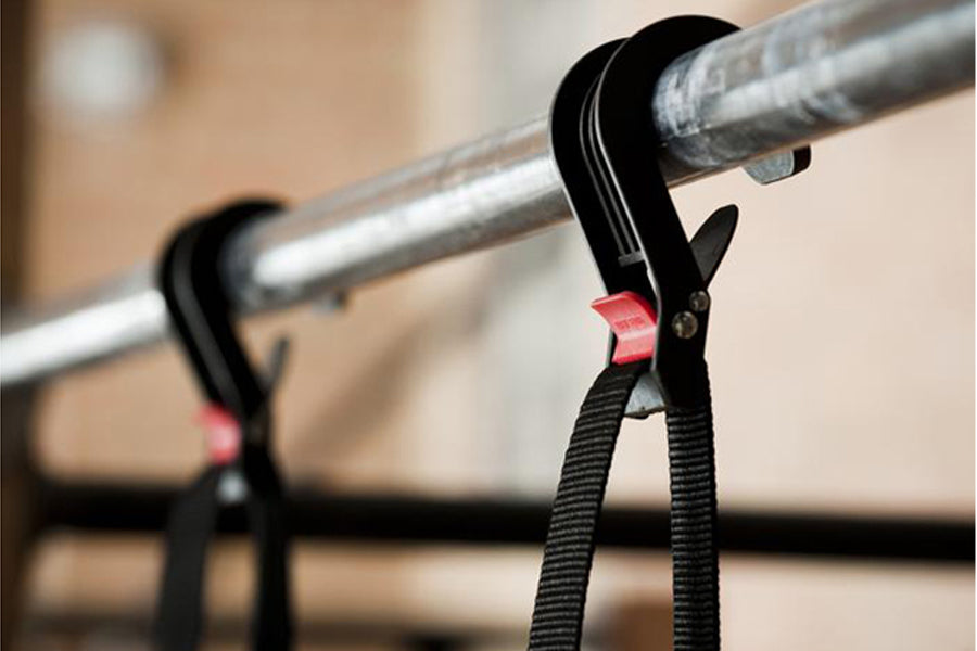 Black pull-up assistance band with red accent detail hanging on metal bar