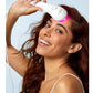 Woman with long reddish-brown hair holding white handheld LED light therapy device with pink light on forehead against blue b
