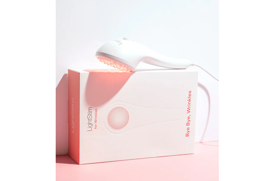 LightStim LED light therapy device with white and pink packaging labeled "For Wrinkles" and "Bye Bye Wrinkles" on pink backgr