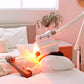 LightStim ProPanel LED light therapy lamp with red and yellow illuminated panel on bedroom nightstand, adjustable white arm a