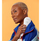 Model holding white and blue LightStim LED light therapy device against shoulder, worn with blue and red jacket on yellow bac