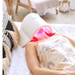 White LED light therapy lamp with red and pink light emitting onto model's face, shown in home setting