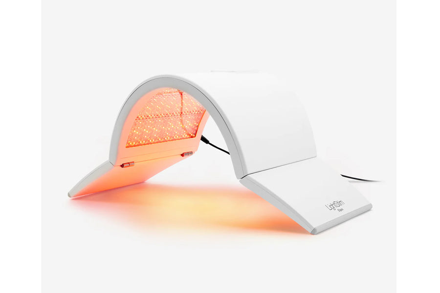 Red light therapy lamp with gray and white base, emitting orange glow, on white background
