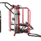 HOIST red and black functional training cage with integrated workout station, hanging heavy bag, and adjustable dumbbells on 