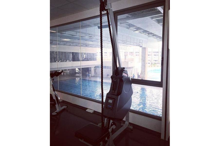 Marpo VLT Compact Rope Trainer in black with digital display, positioned by indoor pool with glass windows