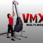 Woman in red shirt using black and gray VMX Multi-Mode rope trainer machine with extended arm mechanism on white background