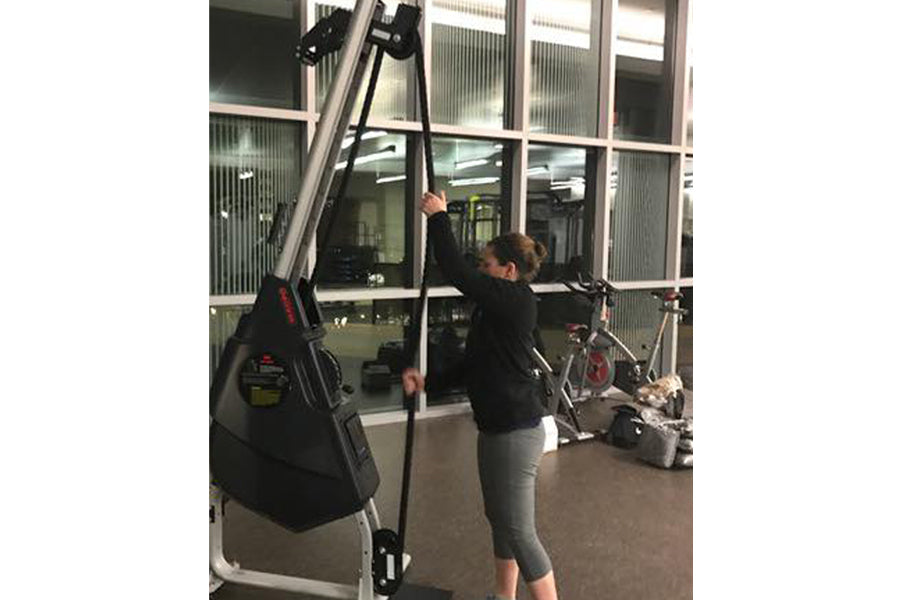 Woman using black Marpo VMX rope trainer with pulley system in gym setting