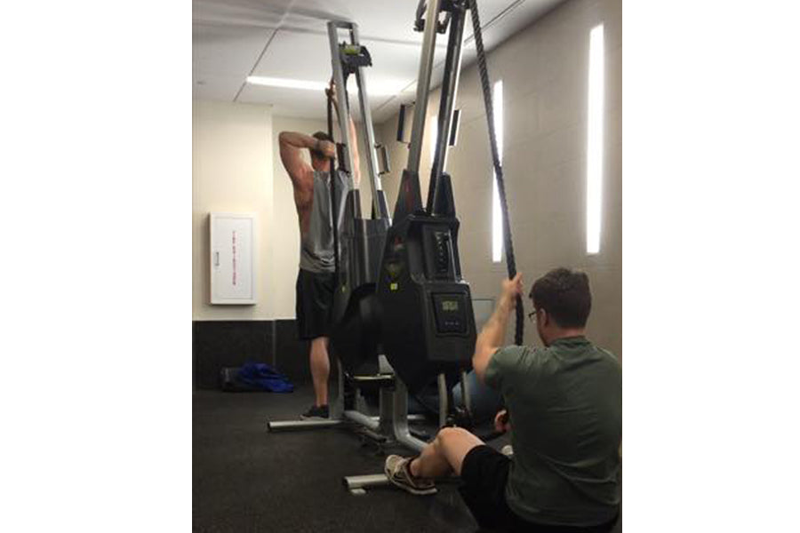 Two people using Marpo VMX rope trainer machine with dual handles in gym setting