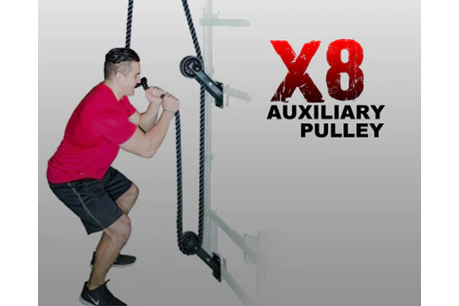 Man in magenta shirt using black rope attached to X8 auxiliary pulley wall-mounted trainer system