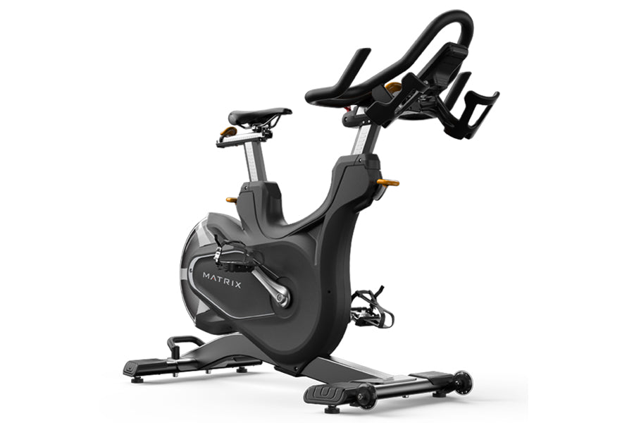 Black Matrix indoor stationary bike with curved handlebars, leather seat, and gold accents on white background
