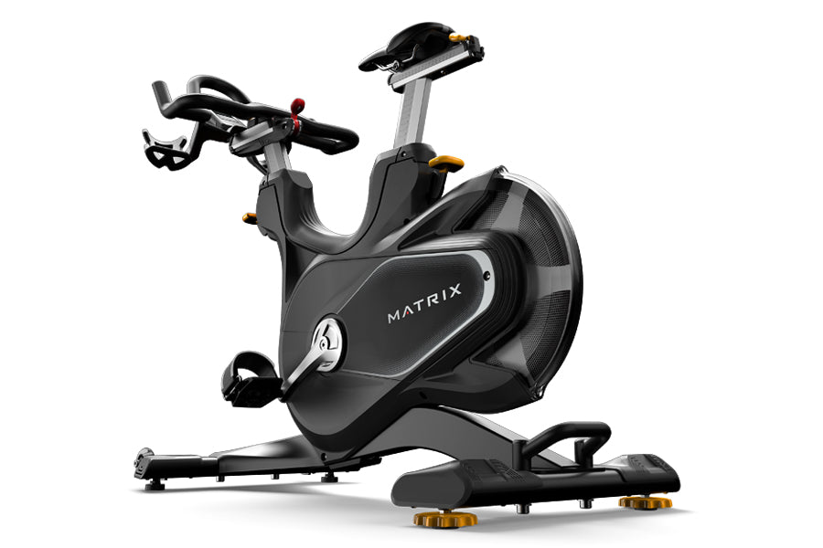Matrix CXP indoor training cycle with black frame, dual handlebars, adjustable seat, and gold foot pedals on white background