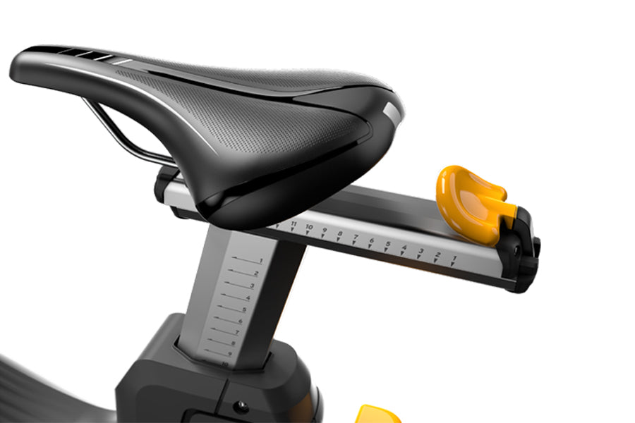 Black padded stationary bike seat with yellow resistance adjustment knob on gray metal post, on white background