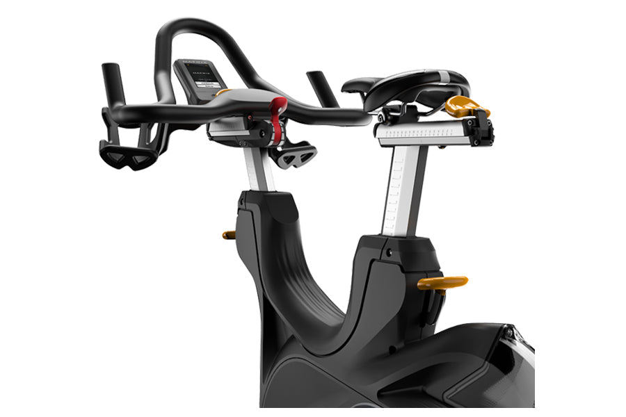 Black and silver stationary exercise bike with curved handlebars, digital display console, and gold accent handles on white b
