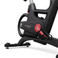 Matrix IC7 Indoor Club Group Cycle close-up of red resistance knob, pedal crank, handlebar frame, and stabilizing base