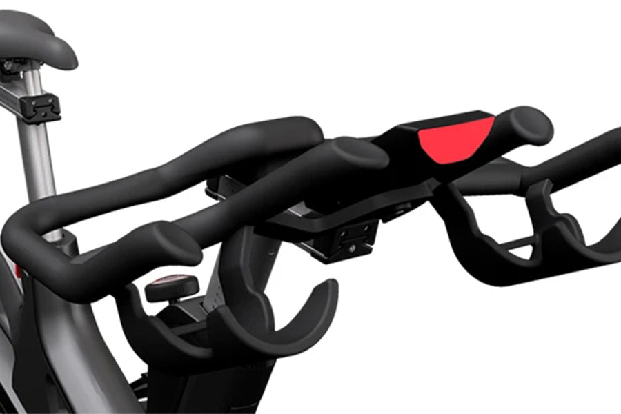 Black and red stationary indoor cycling bike with padded seat, curved handlebars, and adjustable resistance, shown on white b