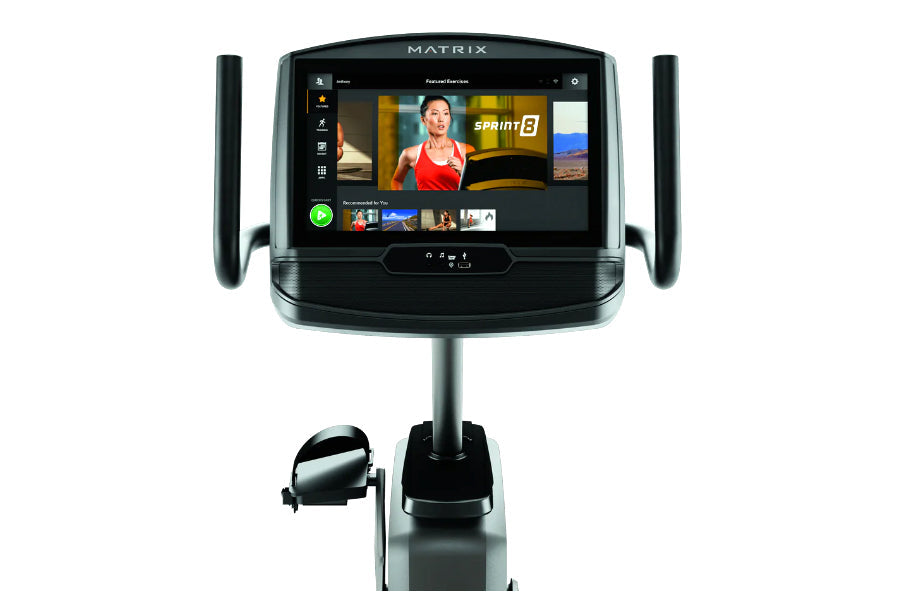 Matrix R30 recumbent exercise bike with black frame, large touchscreen display showing fitness content, and gray handlebars, 